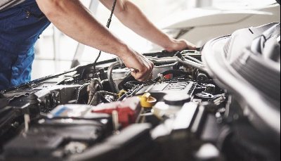 Mechanic working on a car engine under the bonnet.