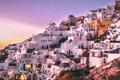 White buildings of Santorini, Greece, on a hillside at sunset.