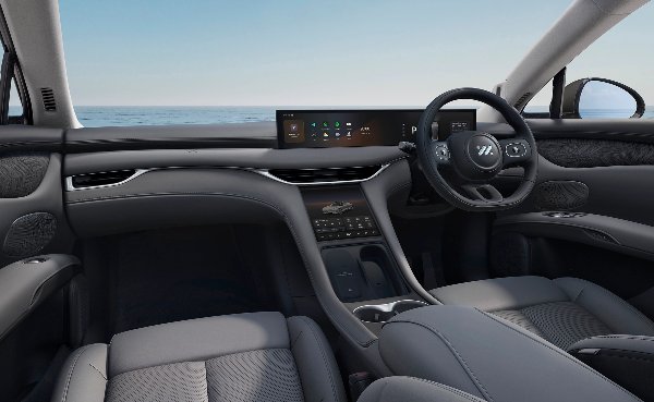 Car interior with grey upholstery, digital dashboard, and modern steering wheel design.