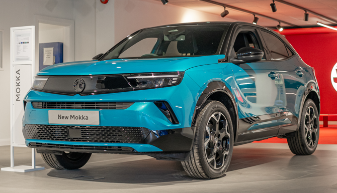 Teal Mokka car displayed in a showroom, viewed from the front left side.