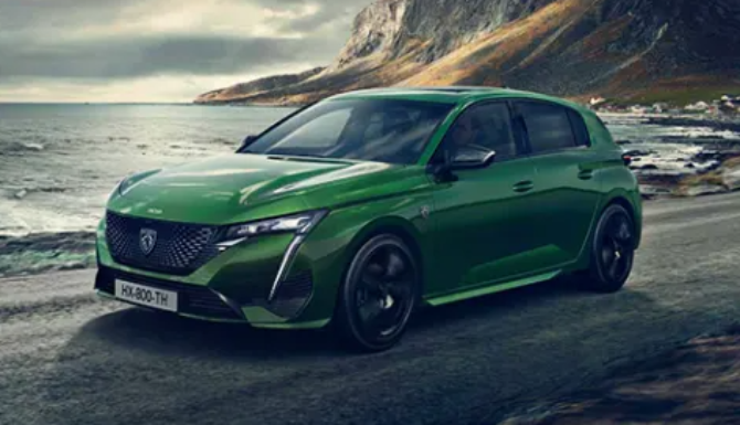 Green hatchback car parked by the seaside.