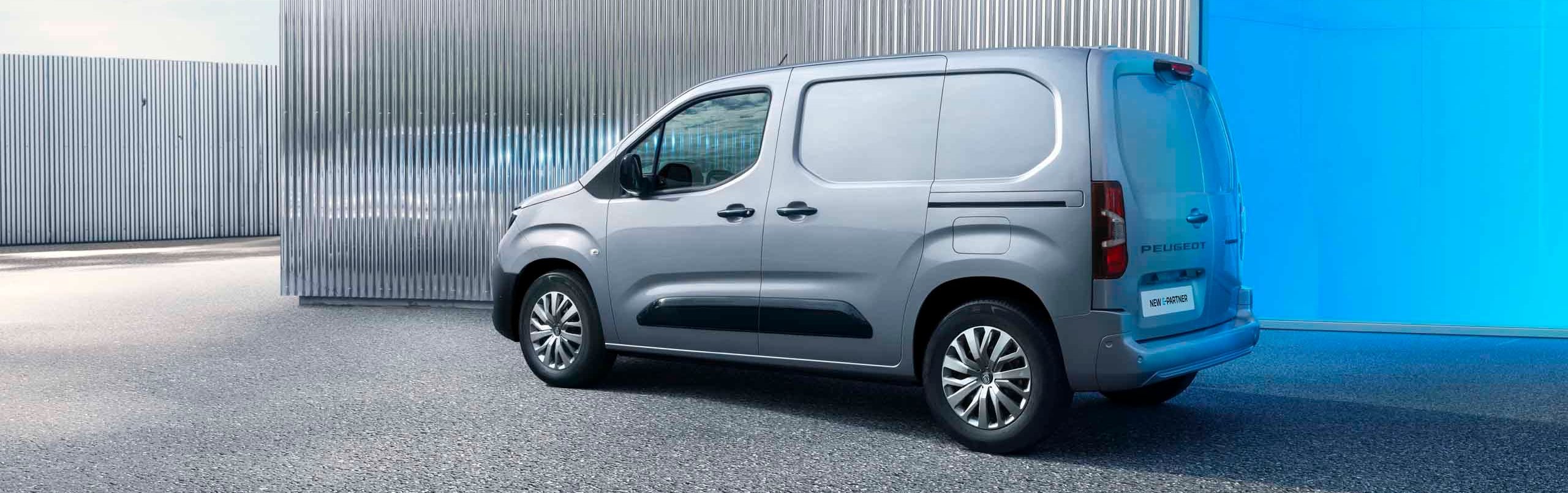 Grey van parked next to a metal-clad building.