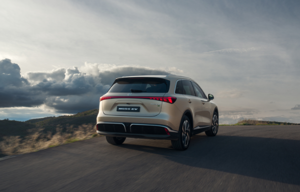 A silver SUV driving on a curved road under a cloudy sky.