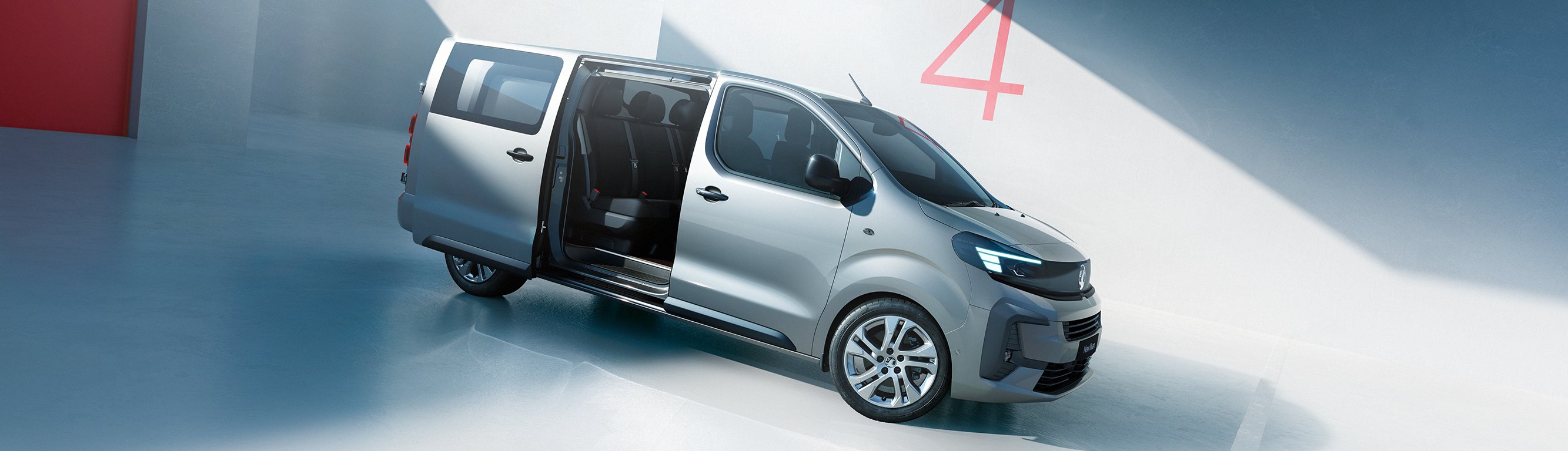 Silver van with a sliding door open, parked in a sunlit area.