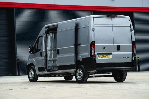 Silver van with side and rear doors open, parked on a concrete area.