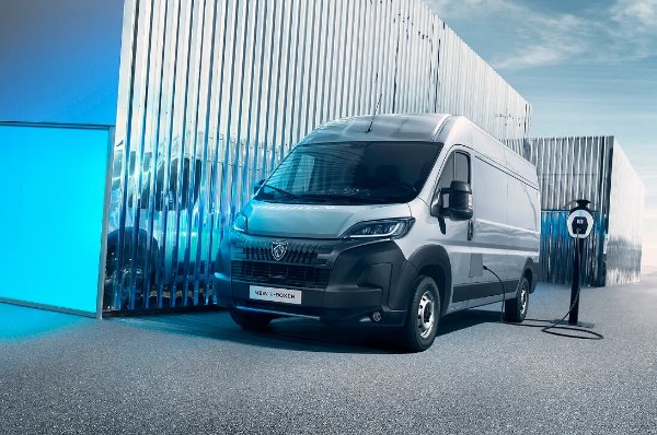 Silver electric van next to a charging station.